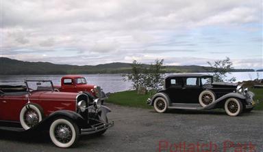 Vintage cars parked alongside the lake